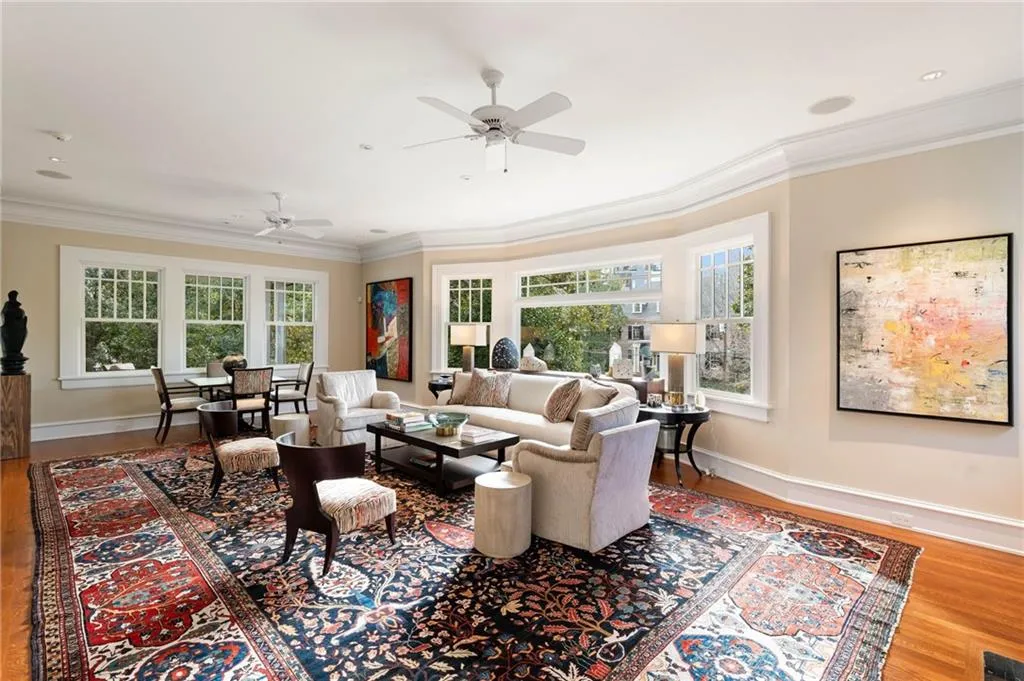 Living room with wood finished floors, crown molding, and ceiling fan