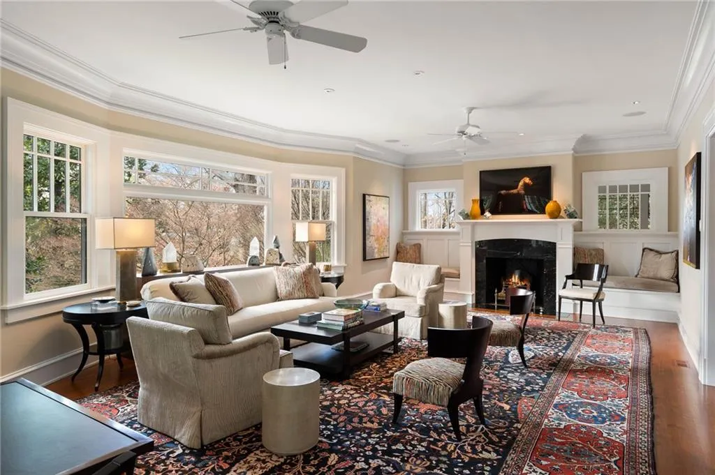 Living area with wood finished floors, ornamental molding, plenty of natural light, a ceiling fan, and a high end fireplace