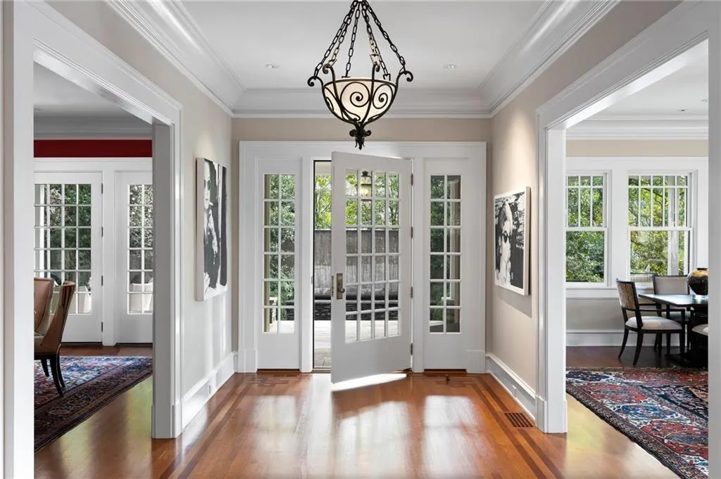 Doorway to outside with wood finished floors, healthy amount of natural light, crown molding, and a chandelier