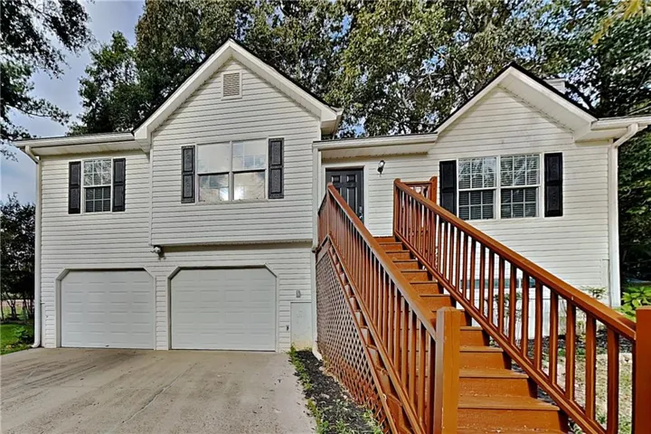 Two-story split-level residence with white siding and a brown-stained exterior staircase