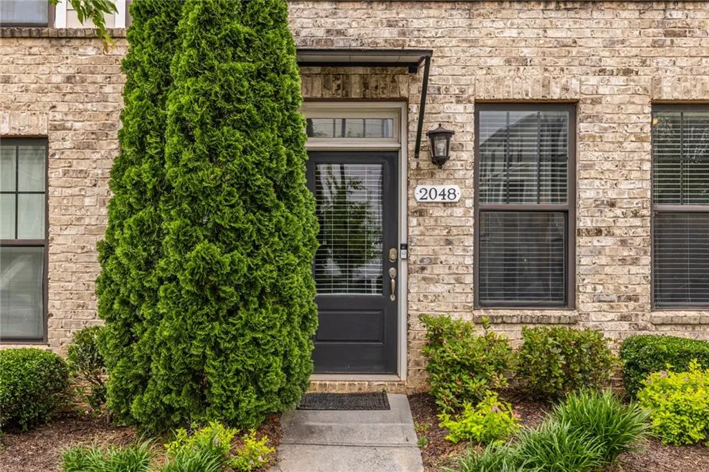 Charming townhome with attractive architectural details and lush greenery, creating a warm and welcoming first impression.