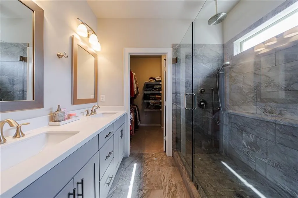 The spa-like bathroom with stone floors, a large walk-in shower with double heads, and a double vanity.