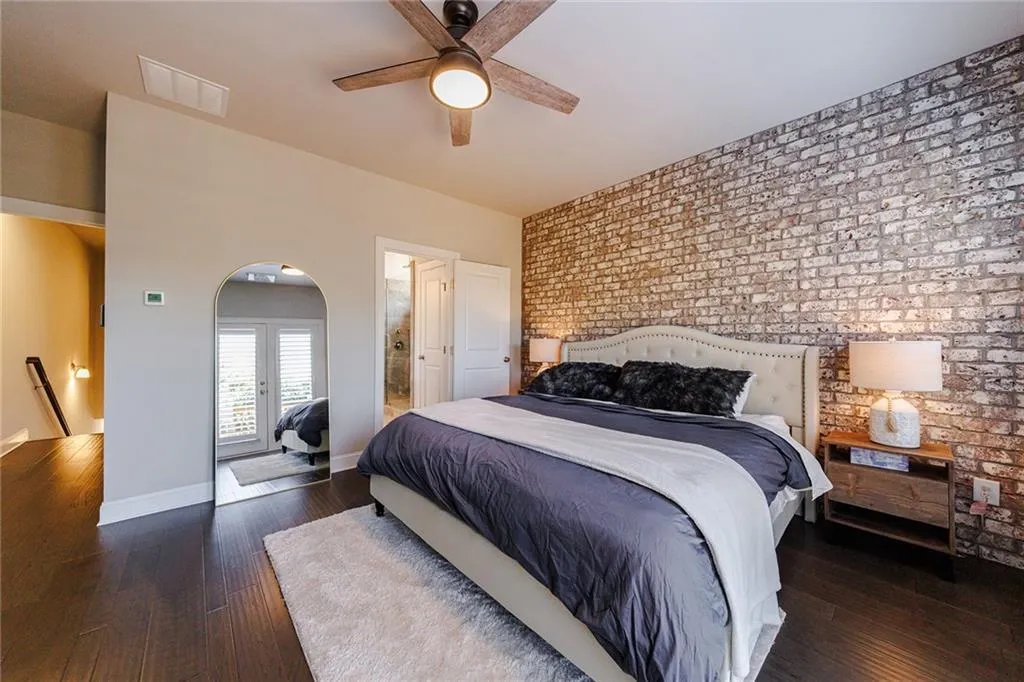 The owner’s suite features an accent wall of brick and a modern ceiling fan.