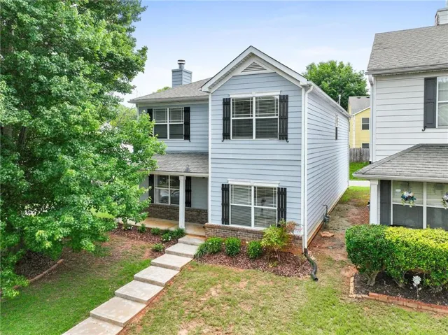 Two-story residence featuring light blue siding, black window shutters, and a covered front porch