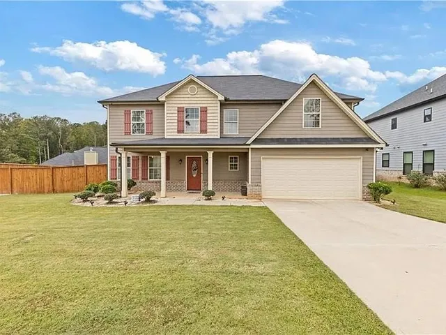 Two-story residence featuring a covered front porch with white columns, a two-car garage, and a concrete driveway