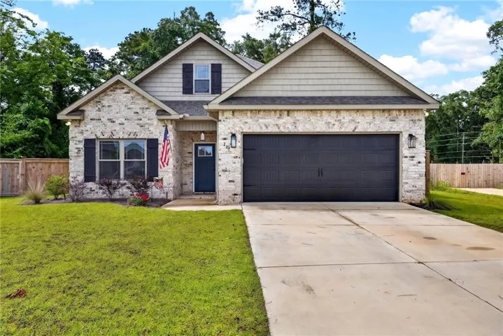Exterior facade featuring light-colored brick with dark shutters, a dark entry door, and a dark garage door