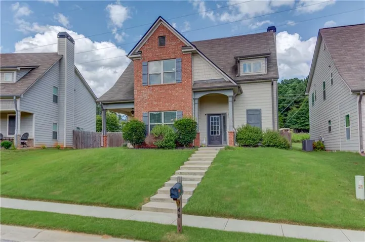 Charming two-story residence featuring a brick and siding facade, a covered front porch, and a dormer window