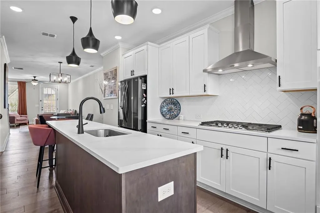 Kitchen features quartz counters, gas cooktop and vent hood.