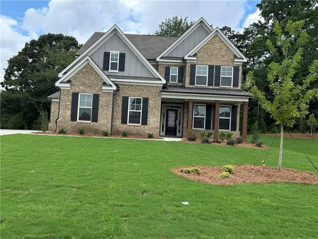 Traditional-style home featuring a brick and siding exterior, gabled rooflines, and a covered front porch with substantial columns