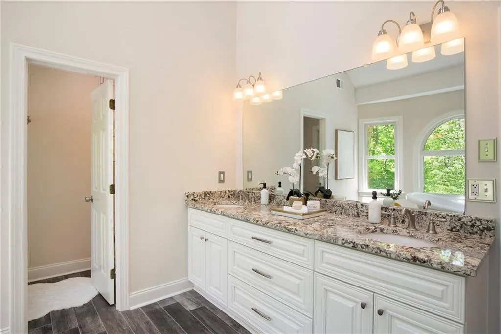 A spacious dual vanity with granite countertops and elegant lighting provides both style and functionality in the primary bath.