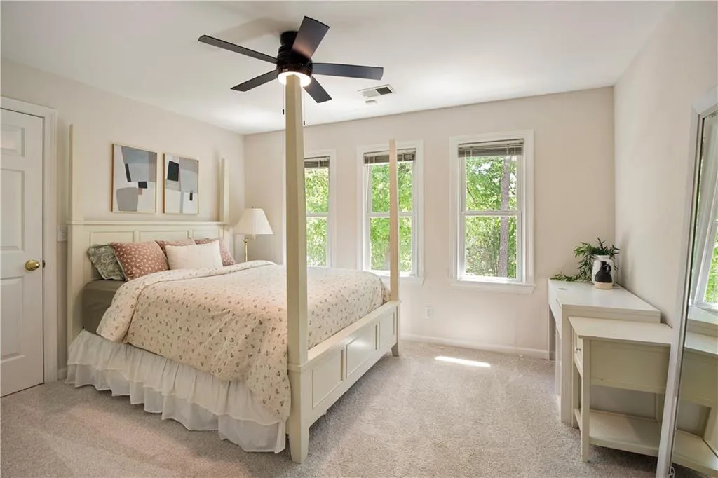 A secondary bedroom is bright and inviting, with large windows that fill the space with natural light and tranquil outdoor views.
