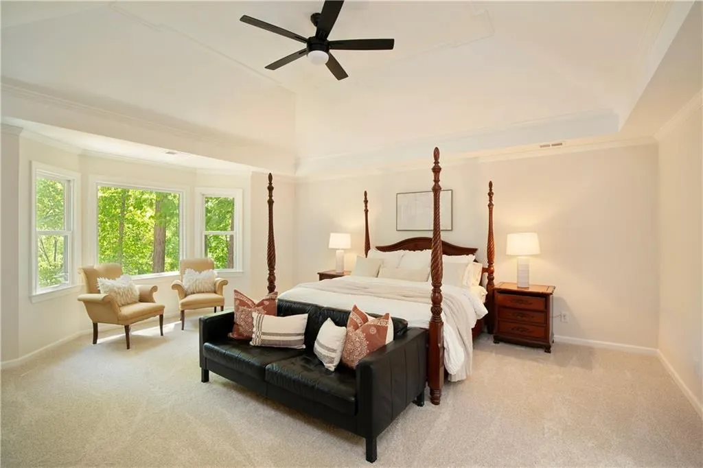 The spacious primary suite offers a private retreat, featuring a tray ceiling, cozy sitting area, and tranquil treetop views.