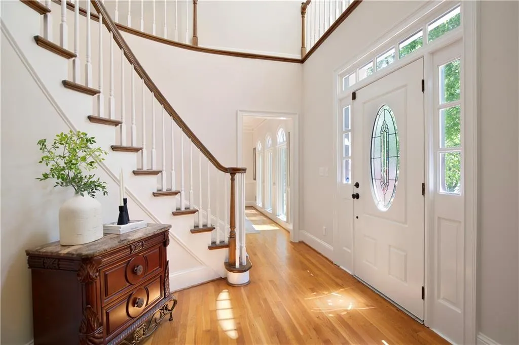 A light-filled two-story foyer introduces the home with refined millwork, warm hardwood floors, and an elegant staircase that sets a sophisticated tone.