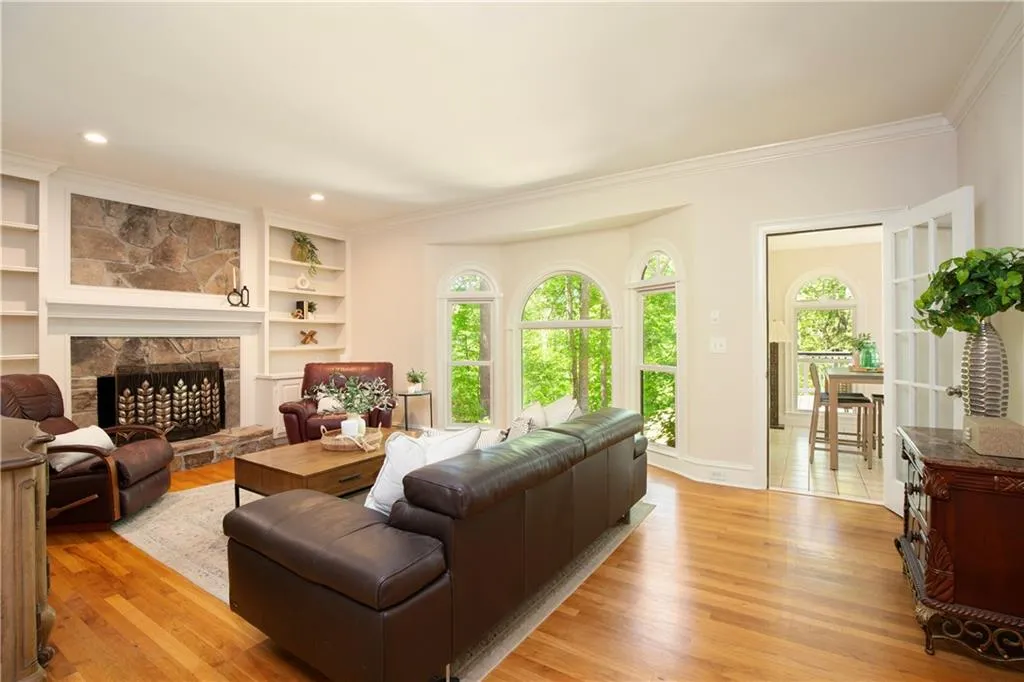 The spacious family room features a striking stone fireplace, custom built-ins, and expansive windows that bring the outdoors in.