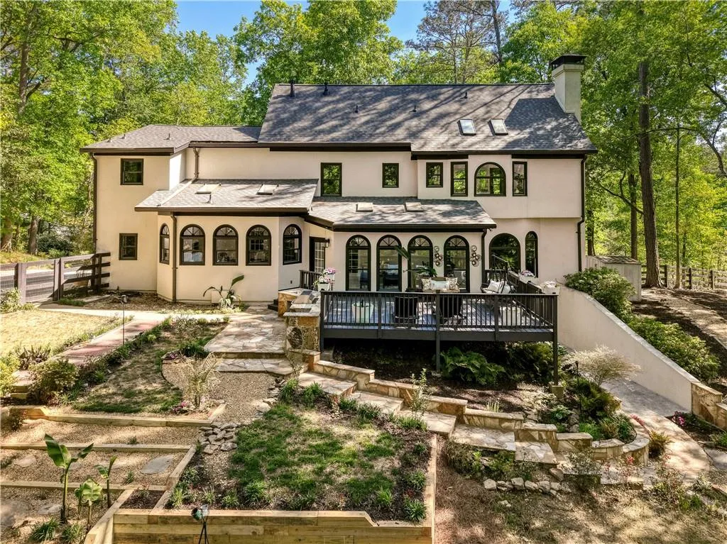 The rear exterior showcases the home’s charming architecture, complemented by a beautifully landscaped yard and elevated deck.