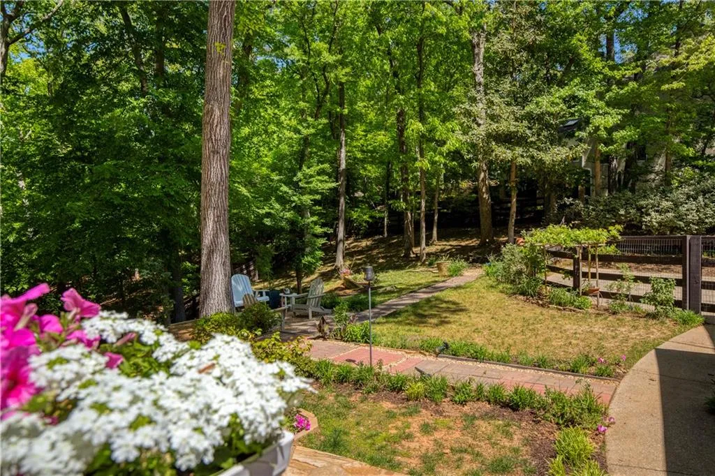 A charming garden path winds through the backyard, leading to inviting seating areas nestled among the trees.