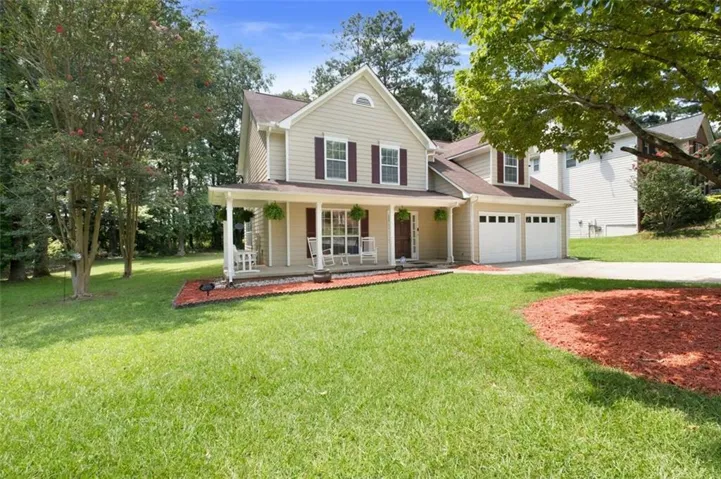 Two-story residence featuring light-colored siding, contrasting dark shutters, and a covered front porch