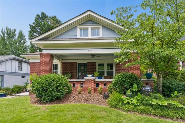 Brick and shingle-sided home featuring a covered front porch with a ceiling fan