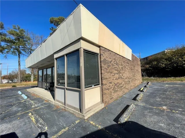 View of property exterior with brick siding and uncovered parking