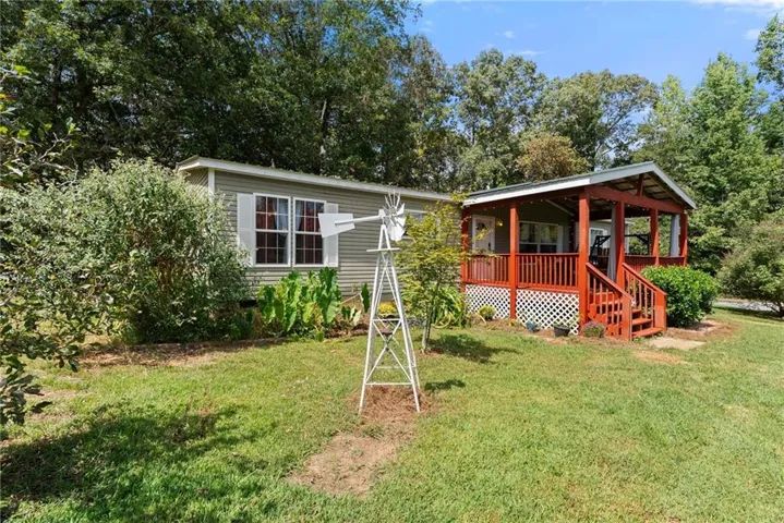 Exterior siding with white window shutters and a covered porch with red railings