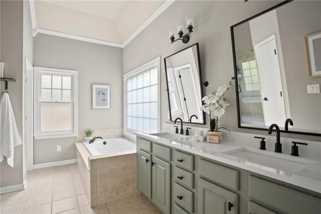 Bathroom featuring double vanity, a bath, tile patterned floors, and ornamental molding