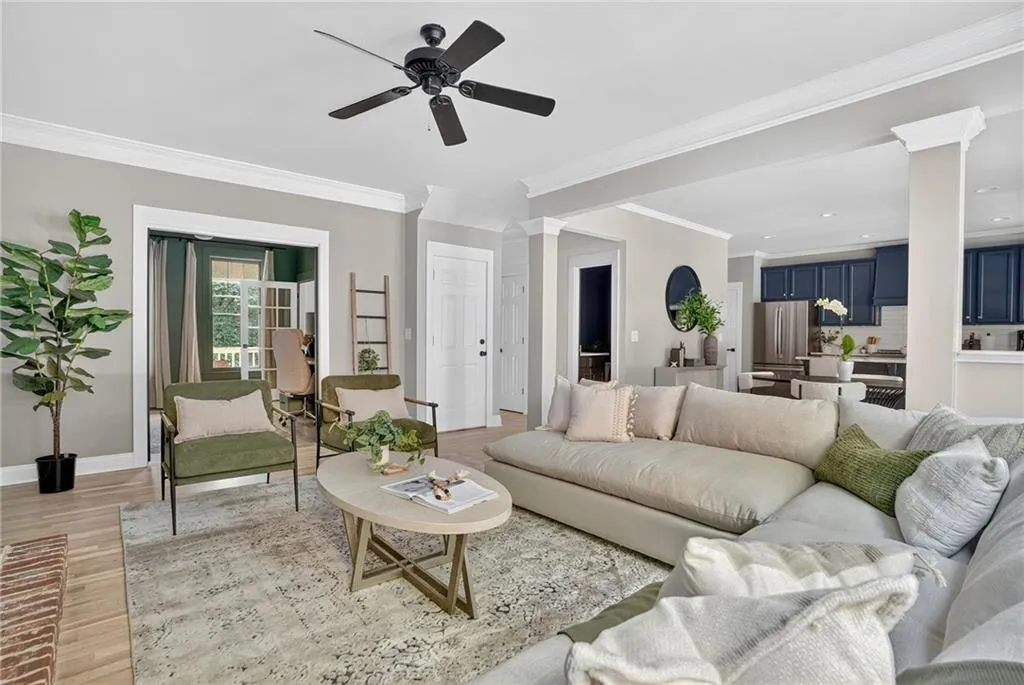 Living room with crown molding, light wood-type flooring, and ornate columns