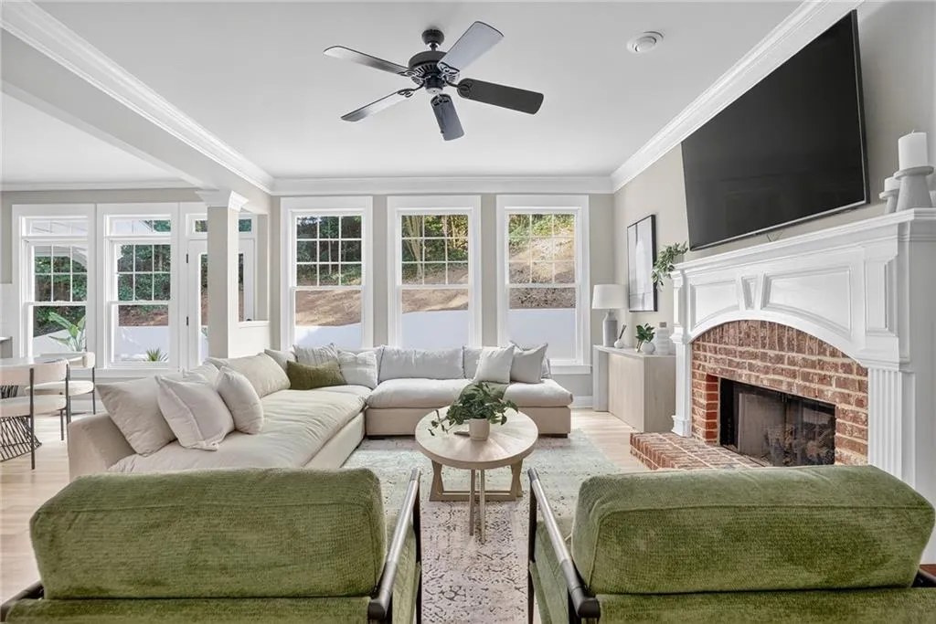 Living room with light wood-style floors, healthy amount of natural light, crown molding, ceiling fan, and a fireplace