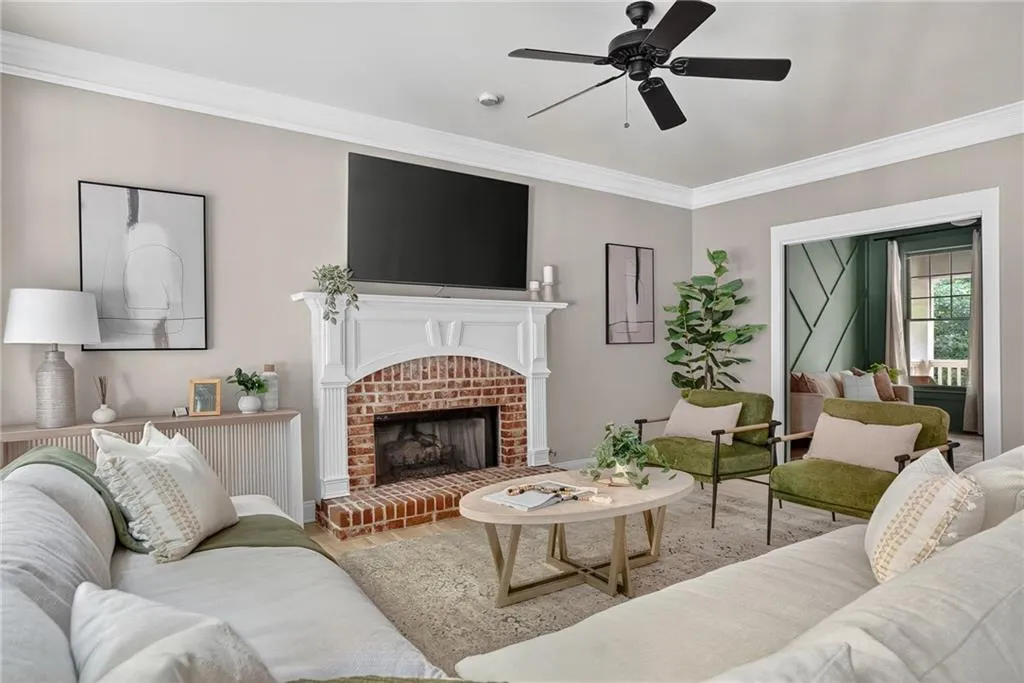 Living room featuring ornamental molding, a fireplace, a ceiling fan, and wood finished floors