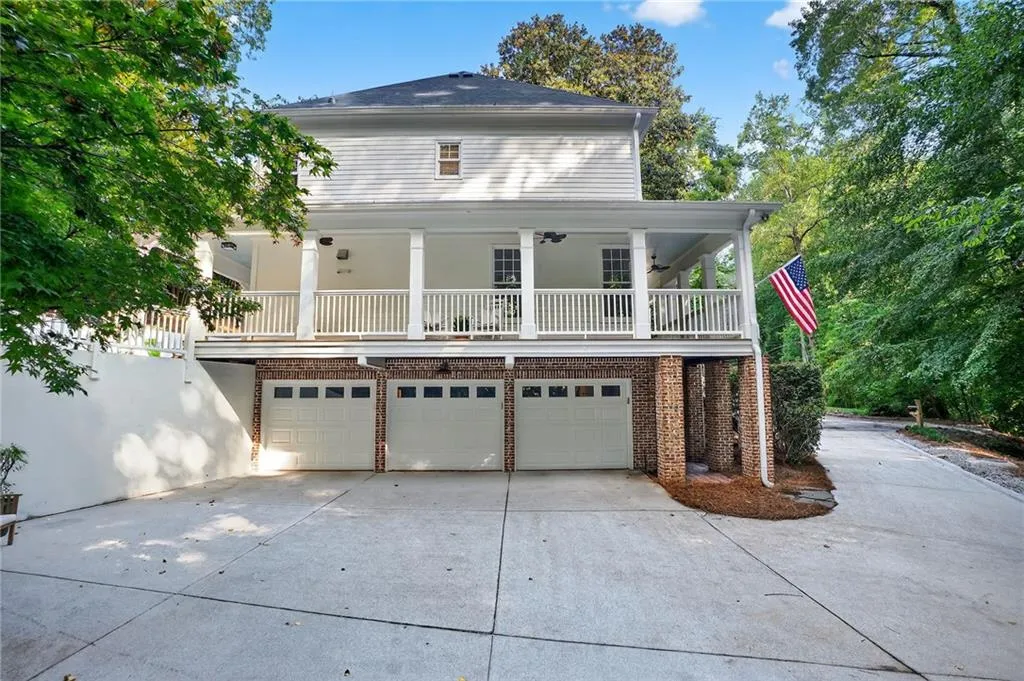 Back of house featuring brick siding, driveway, and a garage