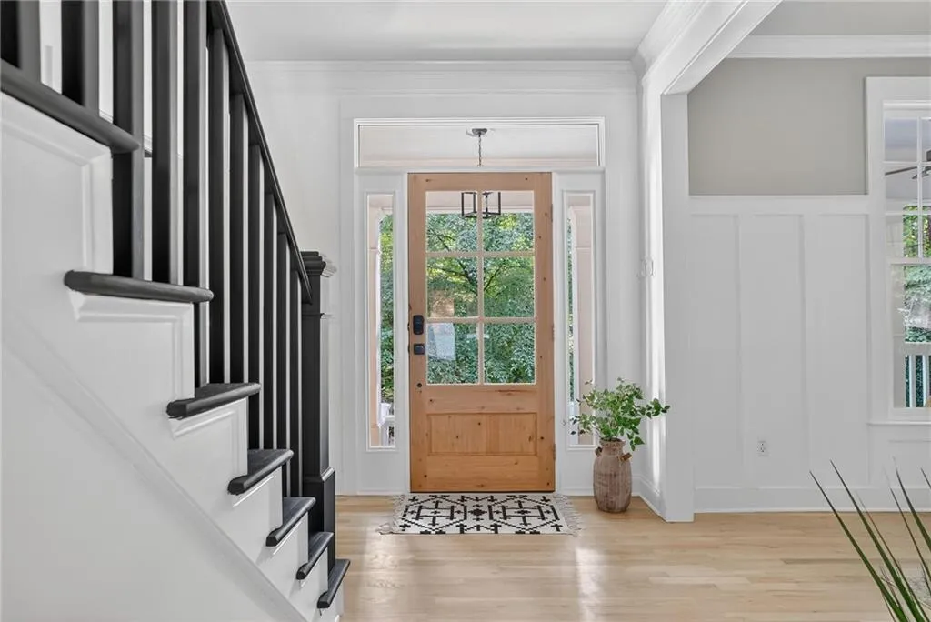Entrance foyer featuring light wood-style floors, crown molding, stairway, a decorative wall, and a wainscoted wall