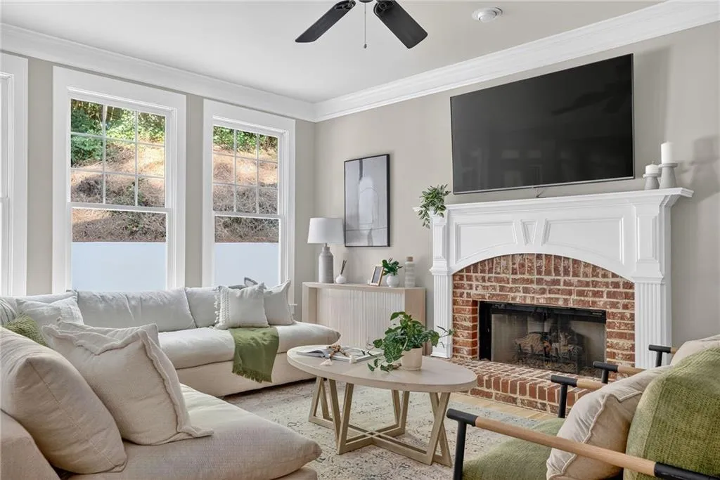 Living room featuring crown molding, a brick fireplace, and light wood finished floors