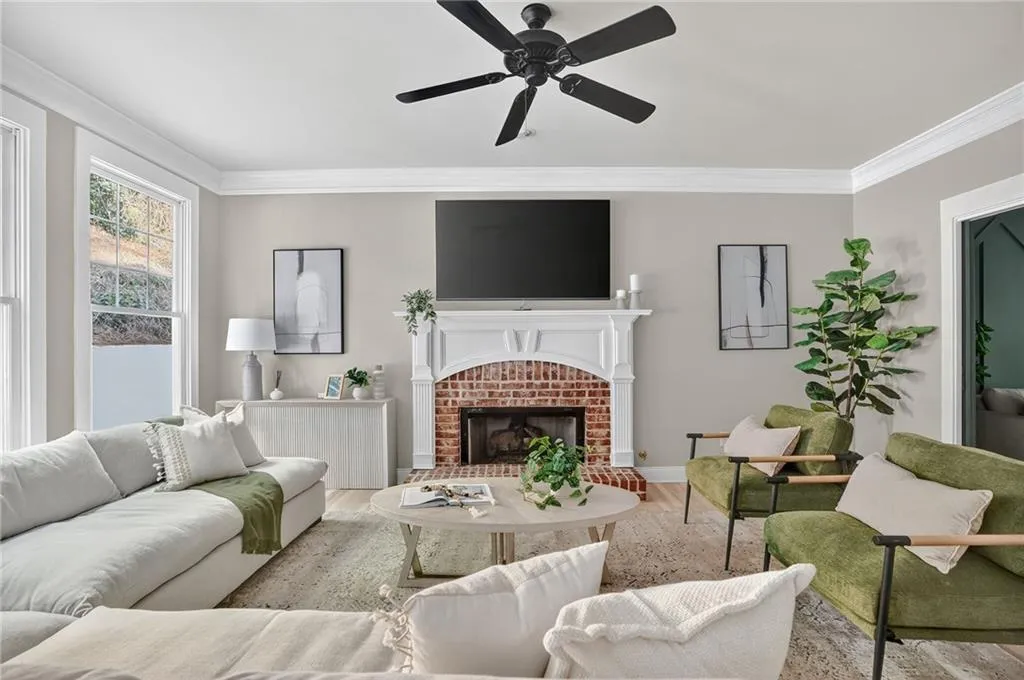Living room featuring ornamental molding, a brick fireplace, wood finished floors, and ceiling fan