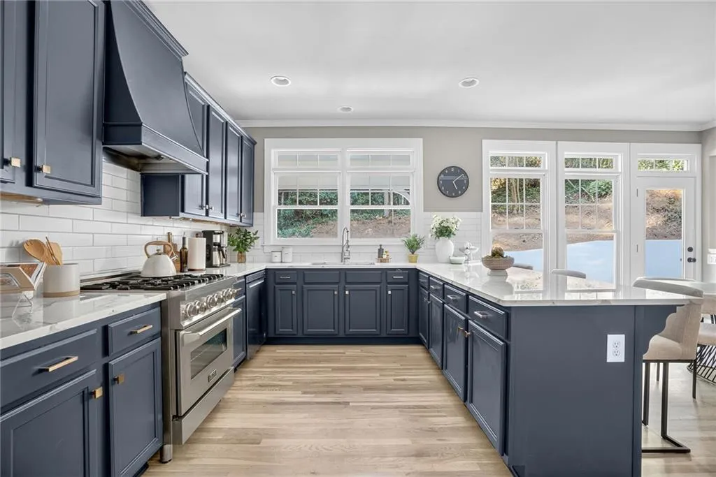 Kitchen with a peninsula, stainless steel range, premium range hood, a breakfast bar area, and backsplash