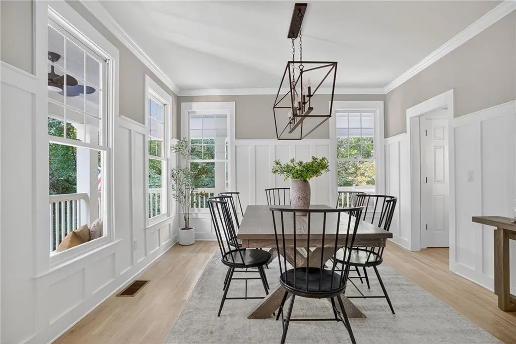 Dining room featuring a decorative wall, light wood-style floors, ornamental molding, wainscoting, and a chandelier