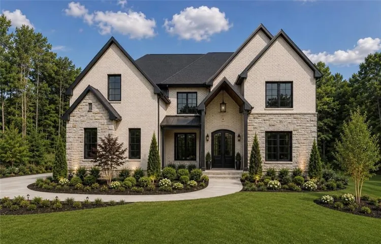Two-story residence featuring light-colored brick and stone veneer, dark trim, and a prominent arched double-door entry