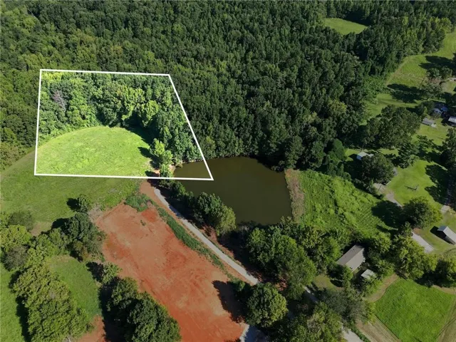 Cleared land area bordered by mature trees and a natural water feature