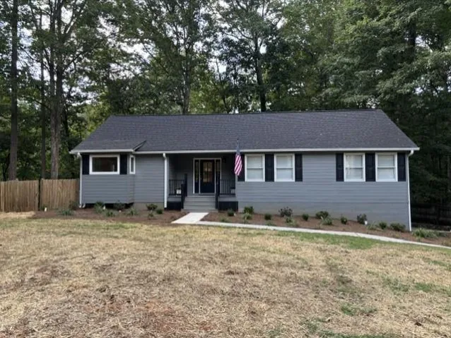 Gray siding exterior with a dark asphalt shingle roof, white trim, and black shutters