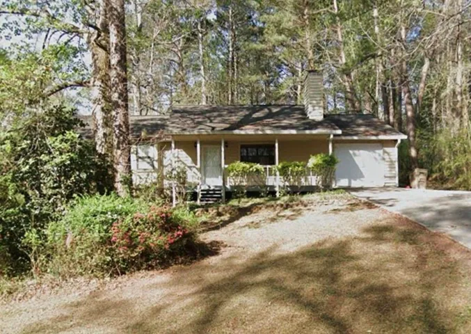 View of front of house featuring a porch, a chimney, driveway, and a garage