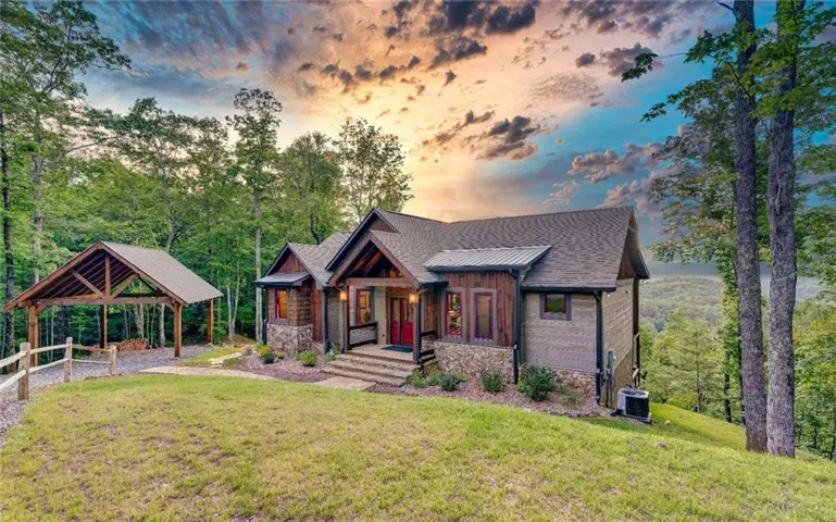 Craftsman-style residence with stone and wood siding, covered front porch, an adjacent covered carport, and a sloped grass lawn