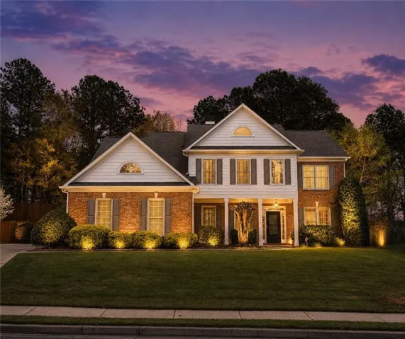 Two-story brick and siding residence featuring a covered front porch, gabled rooflines, and arched window accents