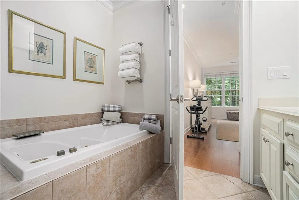 Full bathroom featuring crown molding, vanity, a tub with jets, and tile patterned floors