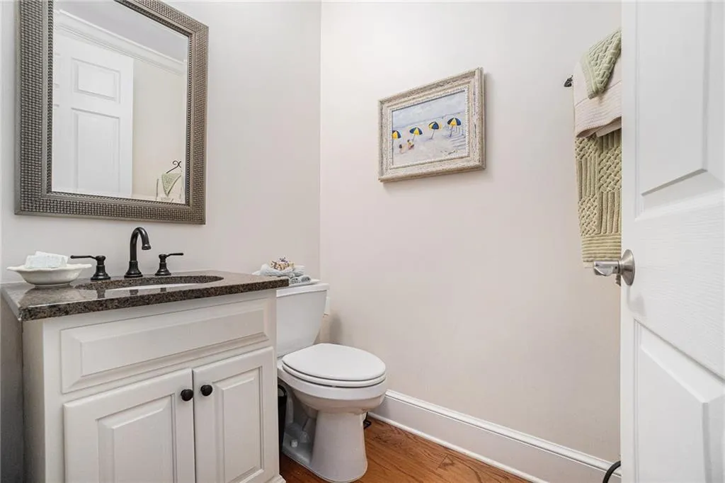 Half Bathroom for guests  features wood finished floors white vanity cabinet, Kohler Plumbing Faucets.