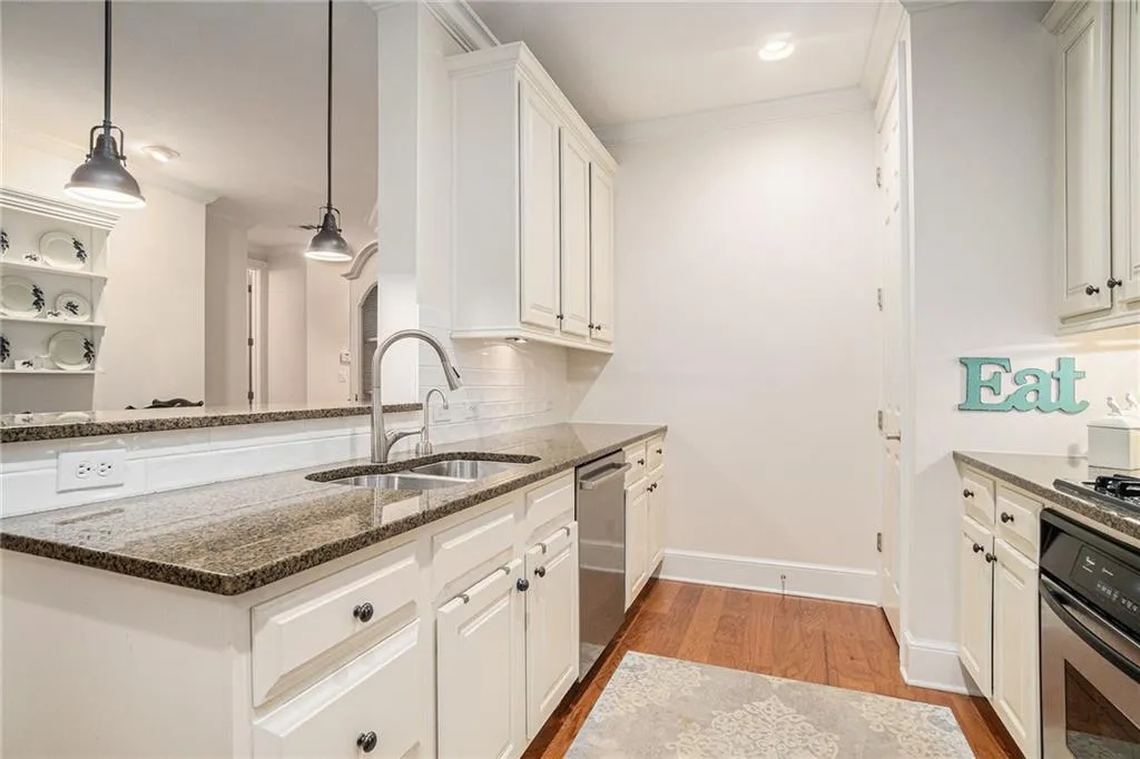 Kitchen featuring light wood-style floors, appliances with stainless steel finishes, ornamental molding, a peninsula, and white cabinets