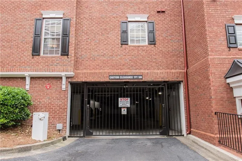 View of exterior garage entry with a gate, brick siding, asphalt driveway, and a garage