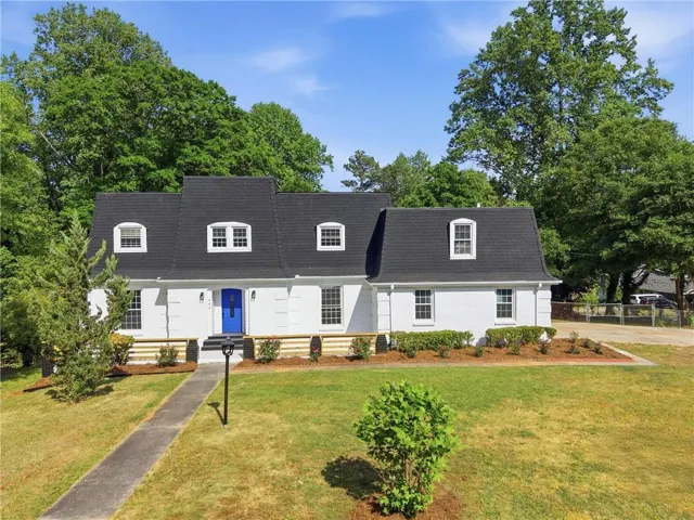 White brick exterior with a dark shingle roof and dormer windows