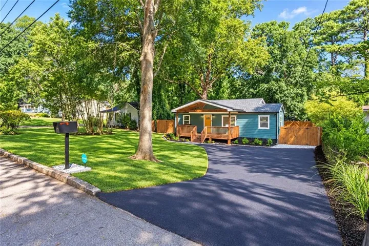 Exterior featuring a teal siding, wood-finish porch, and a paved driveway