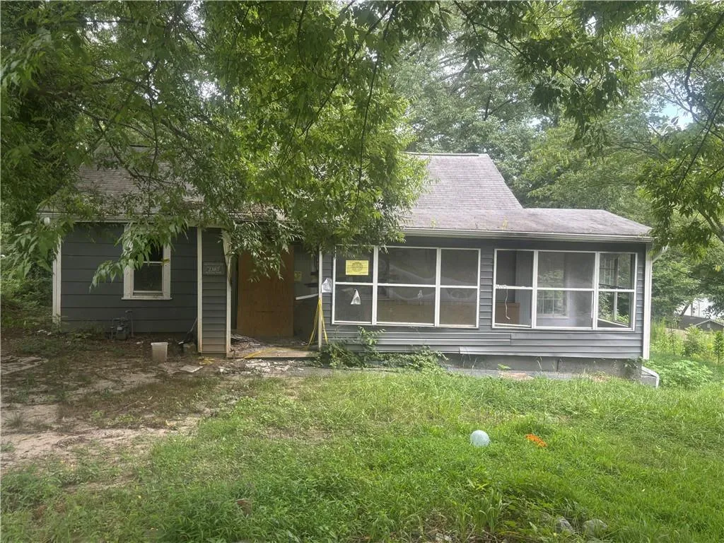 View of front of house with a shingled roof and a sunroom