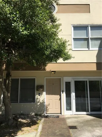 Two-story multi-unit exterior featuring stucco finish, ground-level entry, and an upper-level horizontal window