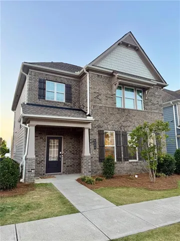 Brick exterior with contrasting siding accents, covered entry porch, dark-paned front door, and a concrete pathway