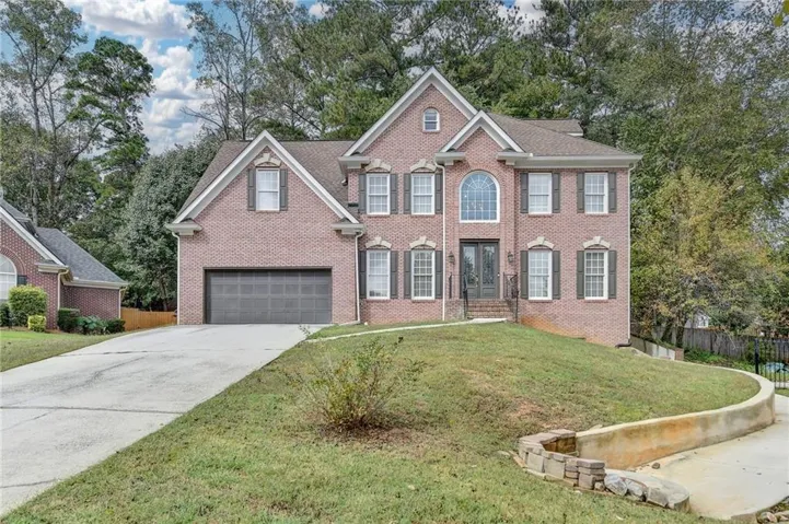 Colonial home with driveway, brick siding, and an attached garage